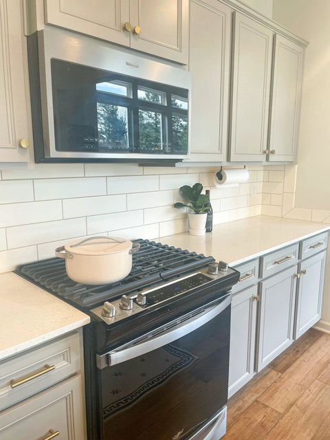 Modern kitchen with cabinets featuring door and drawer pulls 6-inch center-to-center brushed titanium gold finish, pot on stove.