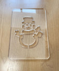 Top Shelf Premium Acrylic Christmas Snowman Router Template For No Sweat Diy Woodworking And Festive Holiday Lantern Build Out Featuring Clean Precision Routing Cutouts Measuring 5.5 By 8 Inches Wide on a wooden surface.