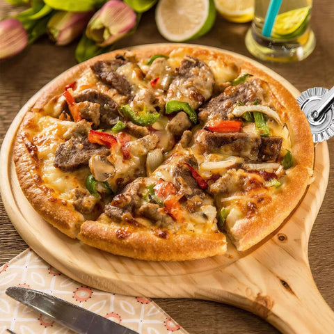 Pastry wheel cutter, front view; fluted stainless steel wheel beside a pizza on a wooden board