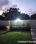 Solar Backyard Flood Lights With 6000mAh Battery illuminating a yard with a fence and trees at dusk.