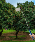 Long Reach 93cm Telescopic Fruit Pollinator Pollen Sprayer With Clear Tank And Lightweight Metal Rod Adjustable From 42cm To 93cm Orchard Pollination Tool For Easy No Bend Operation Farm Ready held in hand in front of orchard.