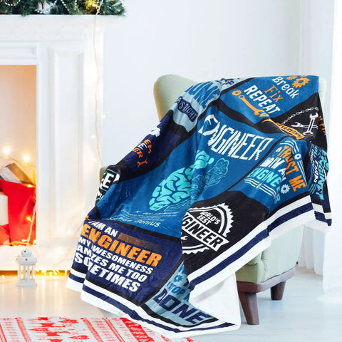 Colorful flannel blanket with engineer-themed designs draped over a chair, part of Engineer Appreciation Gift Set With Blanket, Multi Tool Pen, Keychain And Socks For Men, The Go To Gift For Husbands, Dads, And Grandpas On Birthday, Retirement, Or Fathers Day That Stands Out.