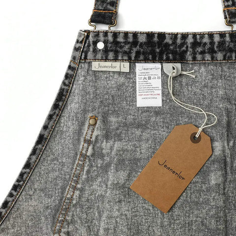 Close-up of Denim Apron With Deep Pockets For Hair Stylists Baristas Gardeners And Craft Pros Cross Back Straps Adjustable From Small To Large Black 100 Percent Cotton Work Apron showing label and tag