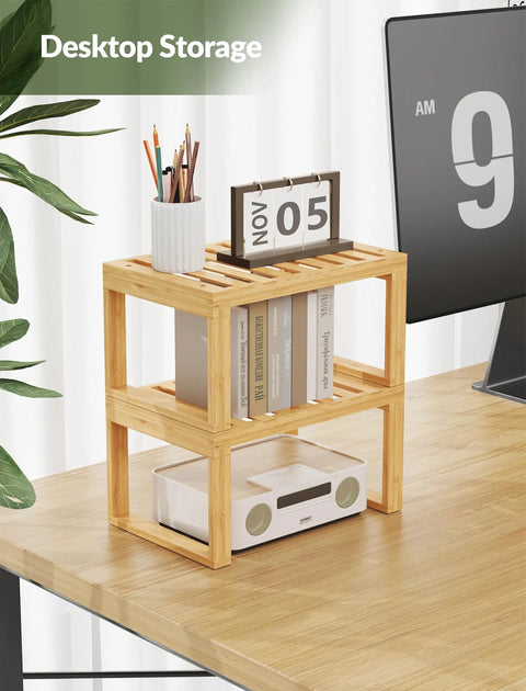 Heavy Duty Bamboo Cabinet Organizer Shelf Two Pack Stackable Kitchen Counter Rack Featuring Slatted Draining Surface To Air Out Dishes And Keep Counters Squeaky Clean on a desktop holding books and pens.