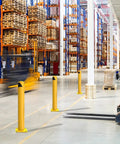 Six Piece Built Like A Tank Thirty Six Inch Yellow Steel Safety Bollard Posts With Four Point Five Inch Diameter and Twenty Four Anchor Bolts For Parking Lots And Driveways in a warehouse setting.