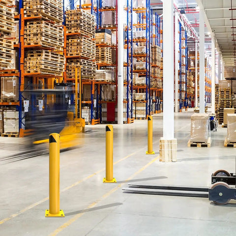 Six Piece Built Like A Tank Thirty Six Inch Yellow Steel Safety Bollard Posts With Four Point Five Inch Diameter and Twenty Four Anchor Bolts For Parking Lots And Driveways in a warehouse setting.