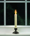 Amber flicker flame LED candle with aged bronze base on window, part of Set Of Four Battery Operated LED Window Candles With Dusk To Dawn Sensor Amber Flicker Flame Aged Bronze Base Uses Two AA Batteries Per Candle Lasts Up To Thirty Days For Cozy Home Ambiance.
