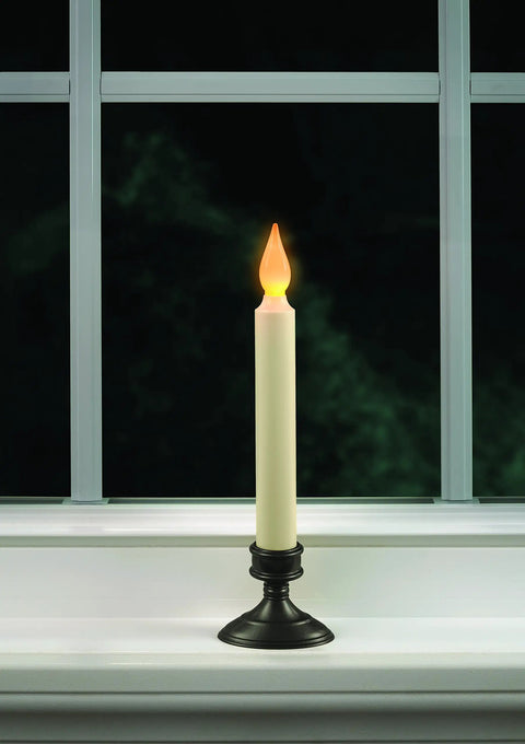 Amber flicker flame LED candle with aged bronze base on window, part of Set Of Four Battery Operated LED Window Candles With Dusk To Dawn Sensor Amber Flicker Flame Aged Bronze Base Uses Two AA Batteries Per Candle Lasts Up To Thirty Days For Cozy Home Ambiance.