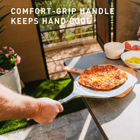 Stainless Pizza Peel With Built In Ridges Serving Board And Pizza Paddle For Ovens 304 Stainless Steel 24 In Long By 11.75 In Wide Lightweight 1.8 Lbs Game Changer for Easy Home Pizza Nights, showing a hand holding the peel with pizza.