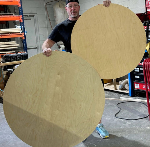 Person holding large wooden circles cut with Circle Cutter Router Jig For Precise Circle Cuts From Seven To Fifty Two And Three Quarters Inches