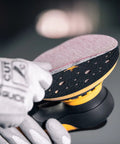 Hand adjusting sandpaper on Top Tier 6 Inch Random Orbital Sander Featuring A Smooth Brushless Motor And Effective Dust Extraction.