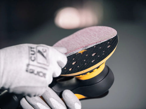 Hand adjusting sandpaper on Top Tier 6 Inch Random Orbital Sander Featuring A Smooth Brushless Motor And Effective Dust Extraction.