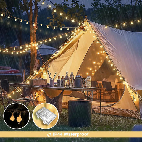 Warm White 100 LED Globe Battery Operated Christmas Lights Indoor With Eight Modes For Cozy Dorm Room Bedroom Or Tree Decor Soft Glow Easy On Battery Perfect For Year Round Holiday Vibes illuminating a camping tent and outdoor setup in the rain.
