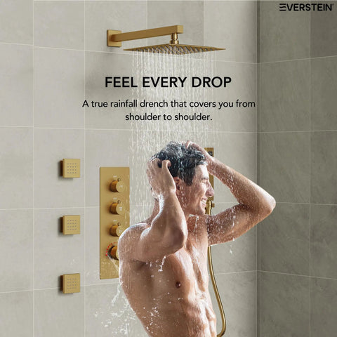 Man enjoying a shower under the EVERSTEIN 12" Rainfall Shower System with Handheld Spray, Brushed Gold.