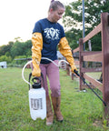 Person wearing Double Nitrile Coated Full Arm Chemical Resistant Safety Glove With Cotton Poly Liner, holding a sprayer outdoors