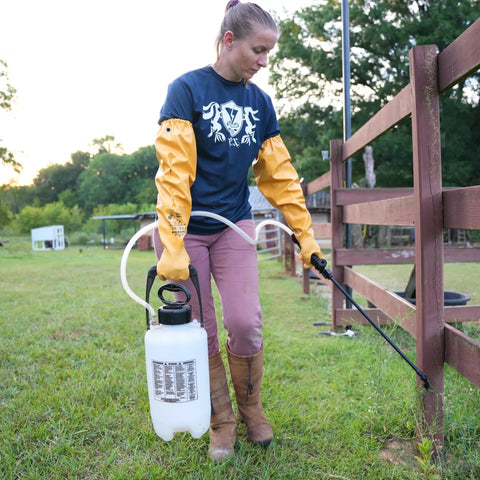 Person wearing Double Nitrile Coated Full Arm Chemical Resistant Safety Glove With Cotton Poly Liner, holding a sprayer outdoors