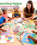 Teacher helping diverse group of children with colorful paper craft projects in classroom, supplies on table