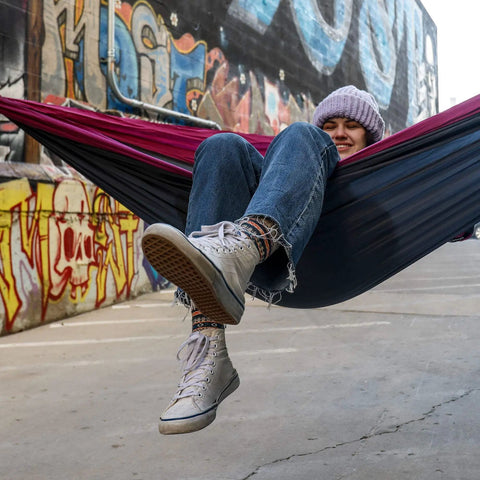 Person relaxing in Double Deluxe Hammock 11 Ft Long, 500 Lb Capacity, Ultra Light Packable Ripstop Nylon, urban graffiti backdrop