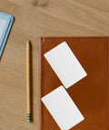 20 Pack Of Top Shelf Blank White Pvc Id Cards Sized At 85X54MM on a leather notebook with a pencil.