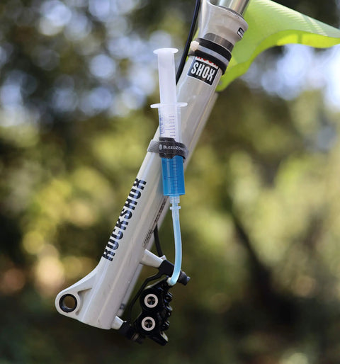 Close-up of Magura Hydraulic Disc Brake Bleed Kit with syringe and hose attached to MTB bike suspension