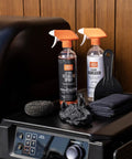 Heavy Duty Grill Cleaning Kit with exterior spray, foaming degreaser, scraper, microfiber towels, and gloves on grill