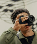 Photographer using Micro Clutch I Plate Hand Strap For Mirrorless Cameras With Low Profile Finger Loop Battery Access ARCA Compatible Baseplate
