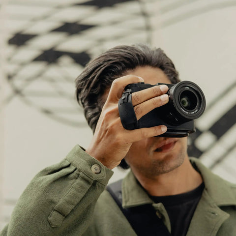 Photographer using Micro Clutch I Plate Hand Strap For Mirrorless Cameras With Low Profile Finger Loop Battery Access ARCA Compatible Baseplate