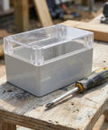 Weatherproof Outdoor Electrical Junction Box With Hinged Cover For Industrial Wiring And Control Systems Plastic Enclosure For No Fuss Tool Free Access Durable All Weather Wiring Box For Equipment Installation And Maintenance. clear plastic box on workbench