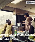 Two people in an RV kitchen using stove with Stove Cover Protector And Oven Liner For Atwood Dometic Triangle 3 Burner Stoves Only Precut For Quick Cleanup Heat Resistant Nonstick Washable Reusable Long Lasting Kitchen Accessory.