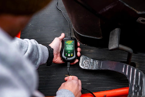 Person using 800 Milliampere SuperSmart Battery Charger And Maintainer in vehicle, showing automatic function with spark proof design.