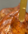 Close-up of a Dishwasher Safe Glass Baster 2 Oz for Juicy Roasts Poultry and Grilling Meats dripping juice on roasted chicken
