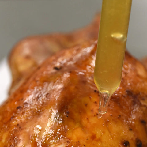 Close-up of a Dishwasher Safe Glass Baster 2 Oz for Juicy Roasts Poultry and Grilling Meats dripping juice on roasted chicken