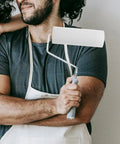 Man holding a mini sponge roller with cushioned handle, ready for painting with Twelve Pack Nifty Little Mini Sponge Rollers.