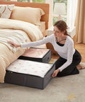 Woman placing comforter in 4 Pack Under Bed Storage Containers 95L Large Capacity With Reinforced Handles For Blankets, Grey