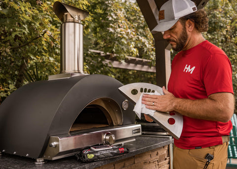 Person using Heavy Duty Cleaning Wipes For Paint Prep And Degreasing, Flat Pack Travel Size Towels For Hands And Tools, Eco Friendly And Unscented, Ideal DIY Garage And Job Site Cleanup on pizza oven tool outdoors.