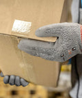 Person wearing 12 Pairs ANSI A5 Cut Resistant Work Gloves With PU Coating For Metal Fabrication, Woodworking, And Construction, holding a box.