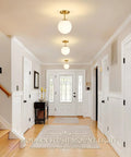 Mid Century Modern Globe Ceiling Light With Frosted Glass Ball And Totally Slick Gold Brass Finish Knockout Semi Flush Mount Fixture Comes With Dimmable E26 Warm Bulb For Hallway Stairs Or Closets, shown in a bright hallway.