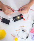 Hands connecting clips to a circuit with E10 Screw Base Miniature Bulbs Warm Yellow Glow 1.5V 2.5V 3.8V 6V Pilot Indicator Lamps.