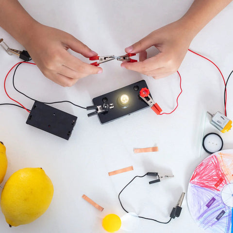 Hands connecting clips to a circuit with E10 Screw Base Miniature Bulbs Warm Yellow Glow 1.5V 2.5V 3.8V 6V Pilot Indicator Lamps.