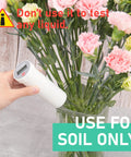 Hand holding Industrial Grade Soil pH Meter With Calibration Free LCD Display near flowers, warning not to test liquids.