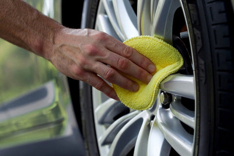 Person using Microfiber Polishing Pads Set For Car Detailing 5 Inch Yellow 6 Pack Ultra Soft Cleaning Pad on a car wheel