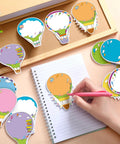 Hot Air Balloon Sticky Notes Bulk Pack, 36 Packs In 9 Styles, 1080 Sheets Total, 2.9 X 3.9 Inch Self-Stick Removable Pads shown on a desk