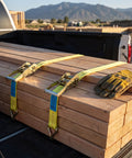 Heavy Duty Ratchet Straps 2 Inch By 17 Foot Rated For Up To 10000 Pounds securing lumber in a truck bed with gloves.
