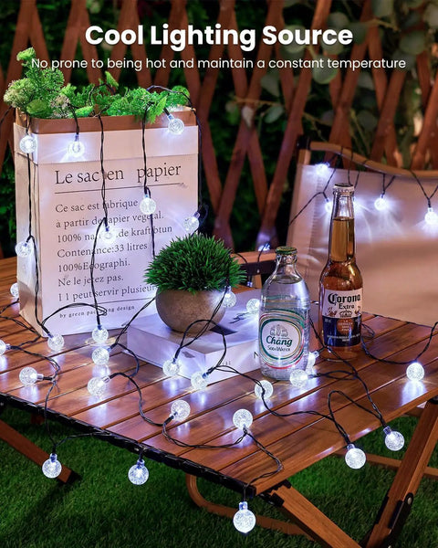2-Pack 72 Ft Solar String Lights With 120 LEDs Waterproof Outdoor Patio Lights Auto On Off 8 Modes Perfect For Garden Yard Porch Wedding Decor Pure White illuminating wooden table setup with drinks and a plant.