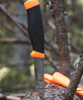 Heavy-Duty Carbon Steel Fixed-Blade Knife with Sheath, 4.1-Inch Blade, shown on tree trunk outdoors