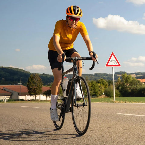 Cyclist on road bike with scenic countryside background