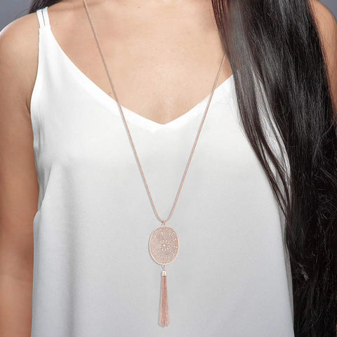 Woman wearing long layered necklace set with oval disk pendant and tassel fringe Y shape in rose gold for everyday or party