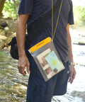 Person outdoors wearing Clear Waterproof Dry Bags Set Of Three Pouches For Phone, Camera, Maps And Documents in yellow frosted PVC.
