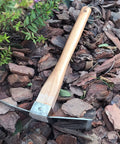 Heavy Duty Stainless Steel Pickaxe Hoe With Wooden Handle for Digging in the Garden resting on mulch