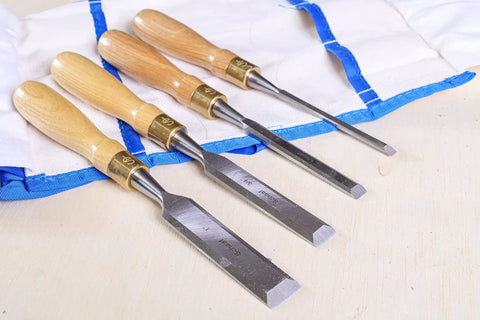 Built Tough 4 Piece Bench Chisel Set For Serious Woodworkers Carved From Top Shelf Chrome Vanadium Steel Blades laid on a tool roll.